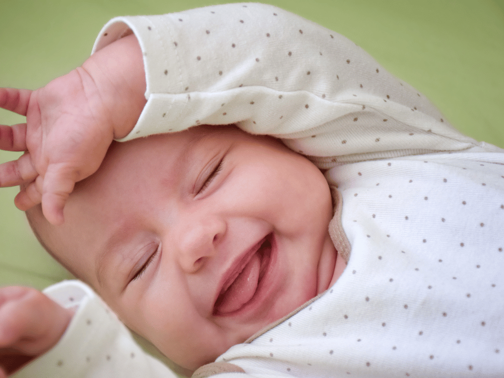 Bebê com os olhos fechados e sorrindo.