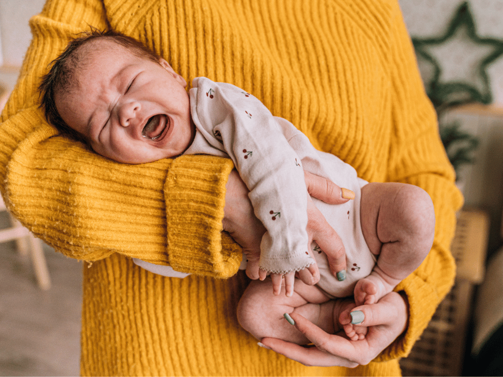 Mãe acalentando bebê chorando com cólica