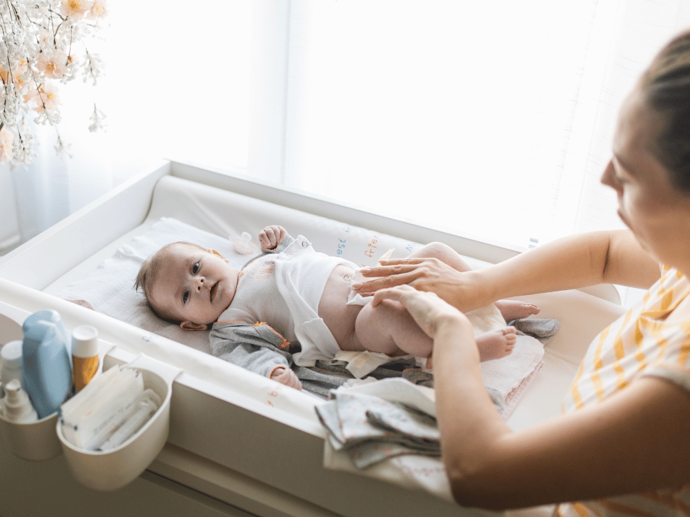 mãe realizando troca de fralda em bebê com assadura. 